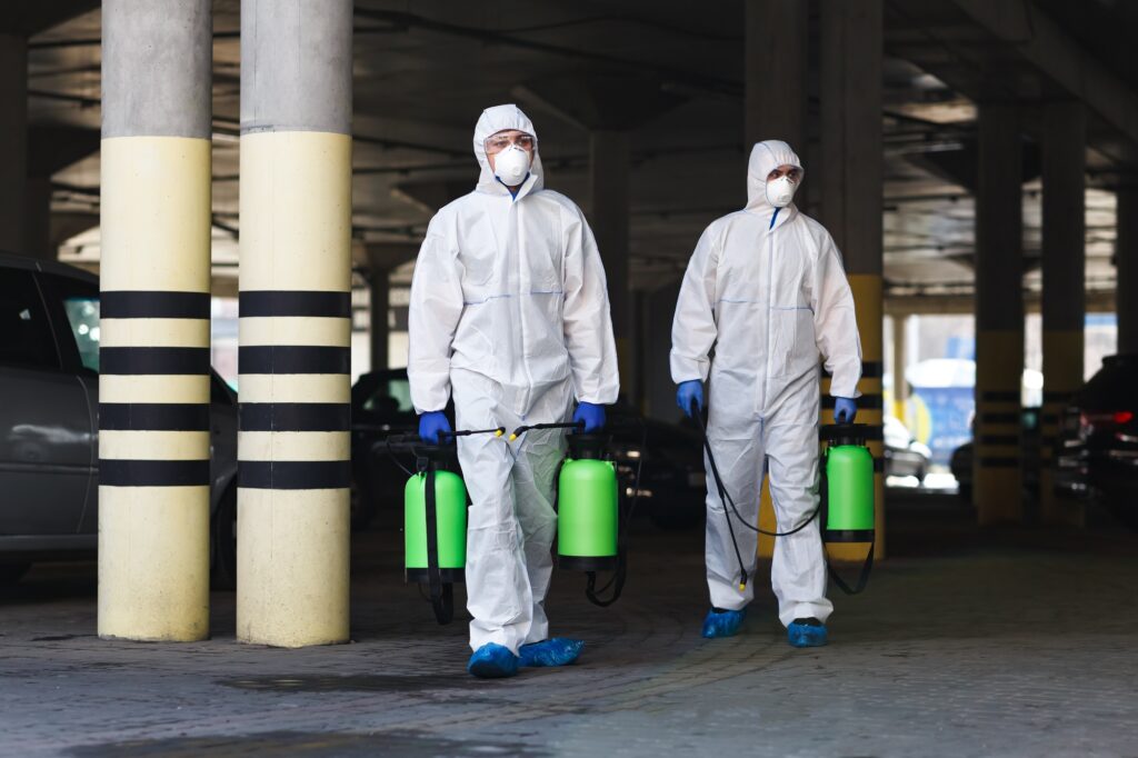 Men in coronavirus suits holding disinfection chemicals outdoor