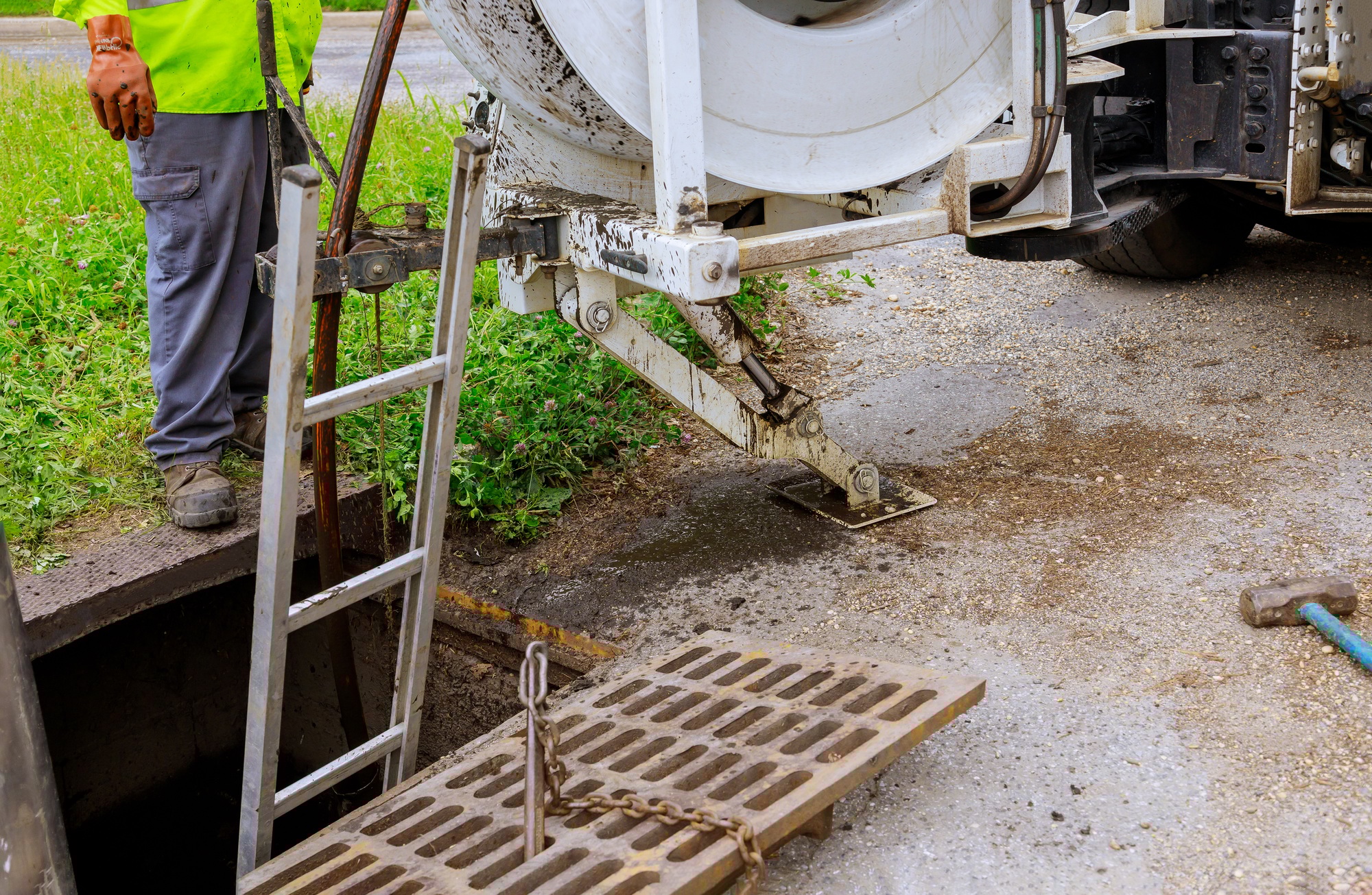 Sewage cleaning workers equipment with sewer on a town street.